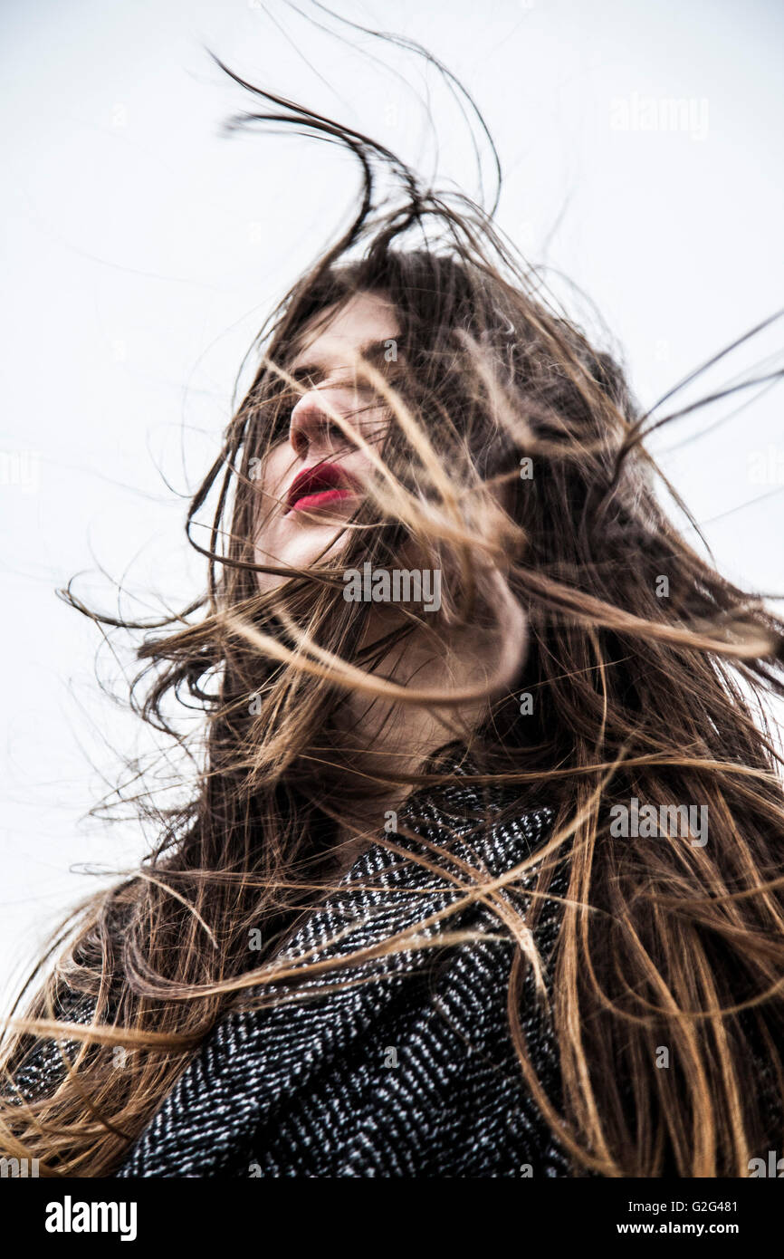 Young Woman with Wind Blowing Hair in Face, Low Angle View Stock Photo