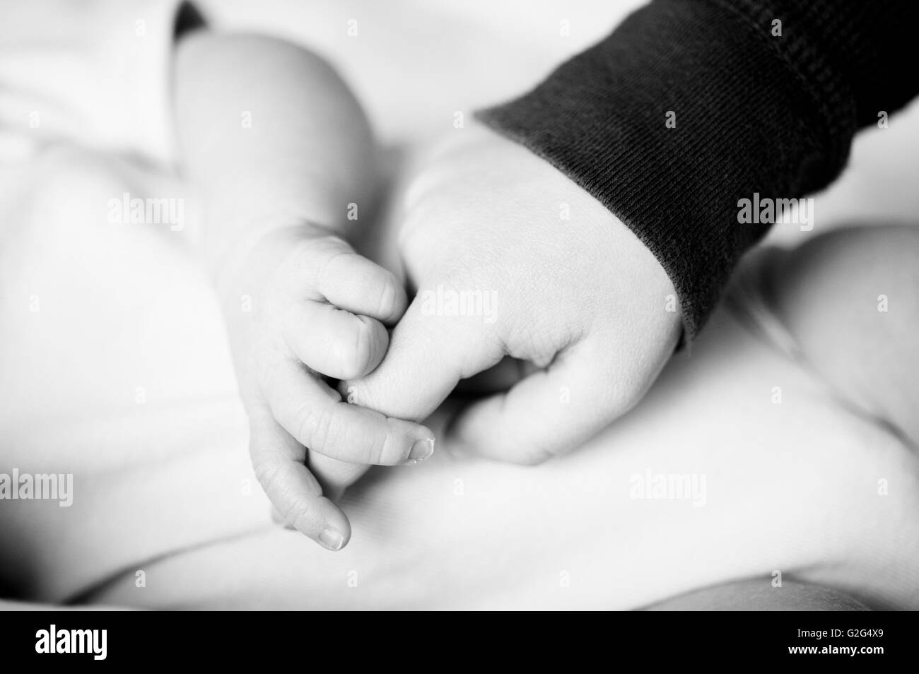 Child and Newborn Baby Holding Hands, Close Up Stock Photo