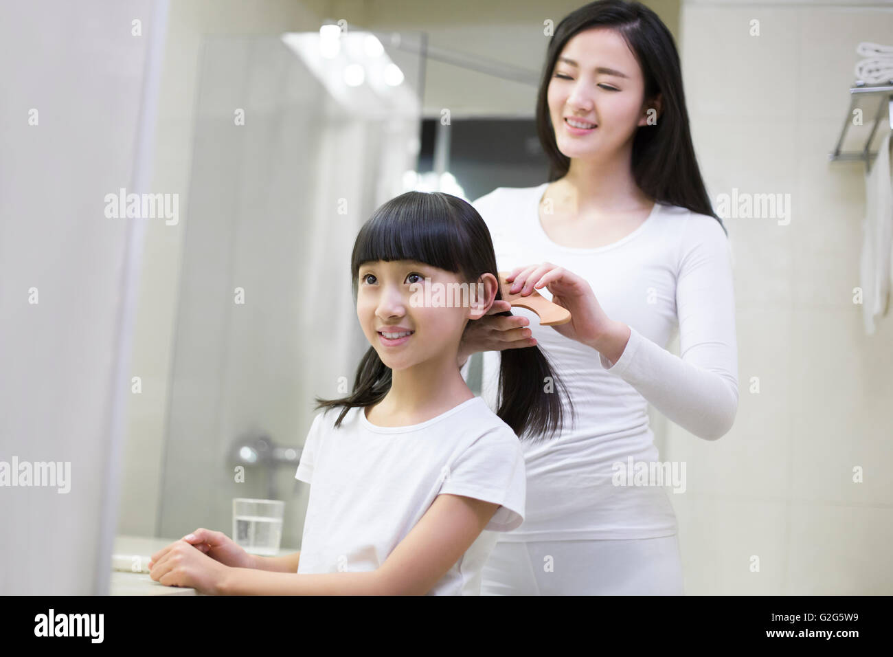 Young mother combing daughter's hair Stock Photo