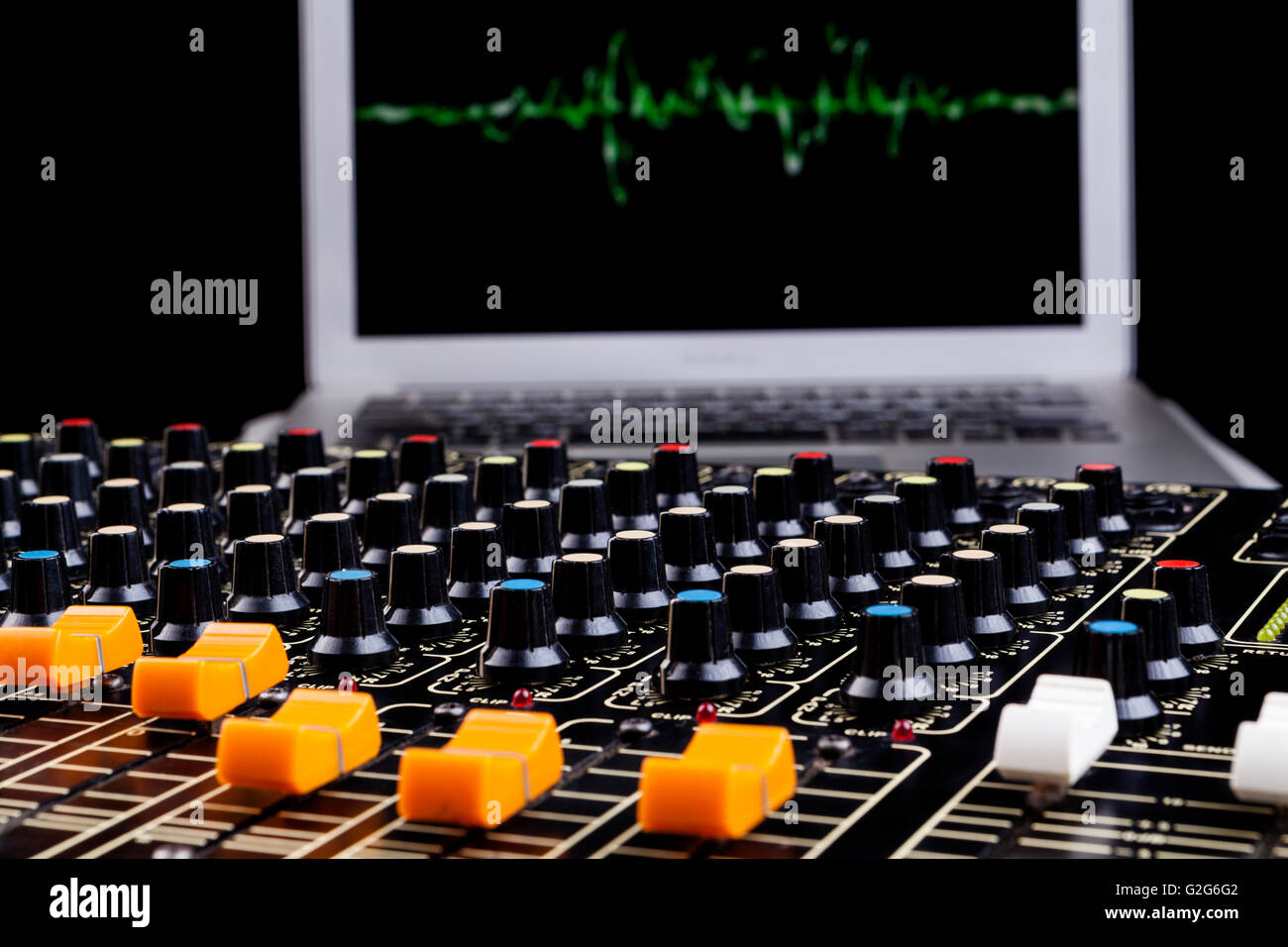 Analog studio sound mixer closeup with laptop and sound wave form in