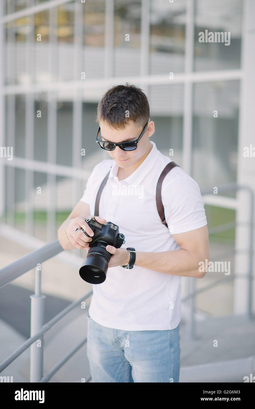 Portrait of young man, tourist with camera in the city. Professional photographer with camera outdoors. Stock Photo