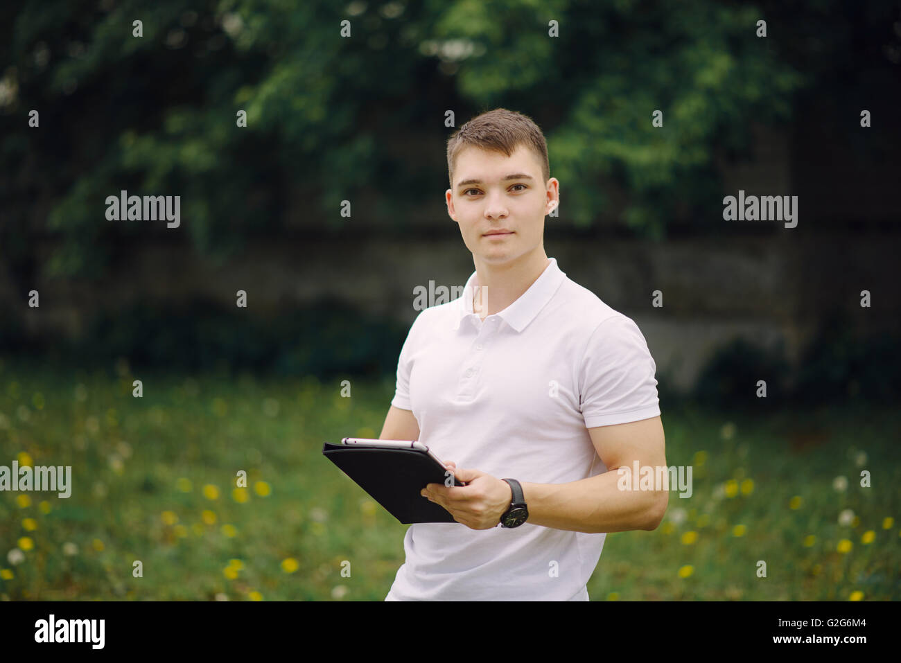 Portrait of standing young man with tablet pc outdoors. Serious young mam using digital tablet pc. Stock Photo