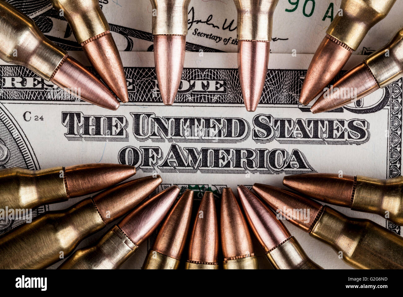 Rifle Bullets pointing at the United States text on a dollar banknote Stock Photo