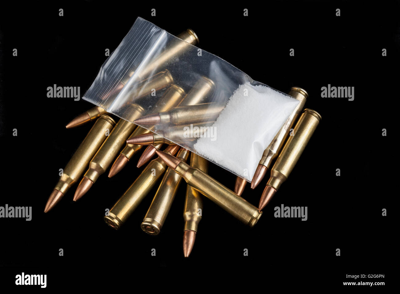 Rifle bullets close-up on black background with a bag of white drug powder Stock Photo