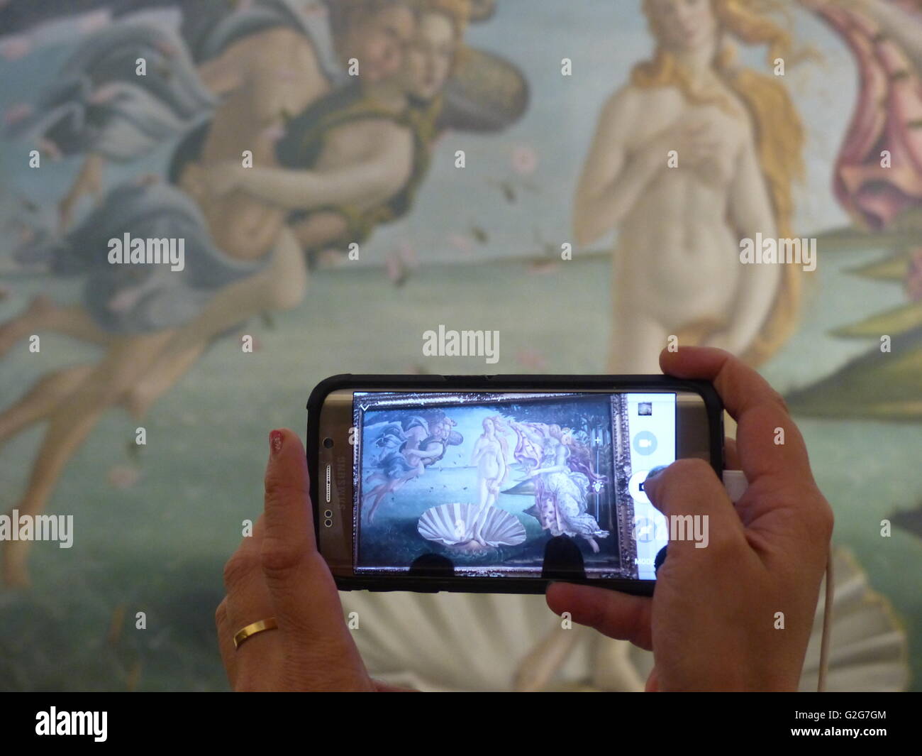 Florence, Italy, Uffizi Gallery. Visitor records Sandro Botticelli on his-her phone. Stock Photo
