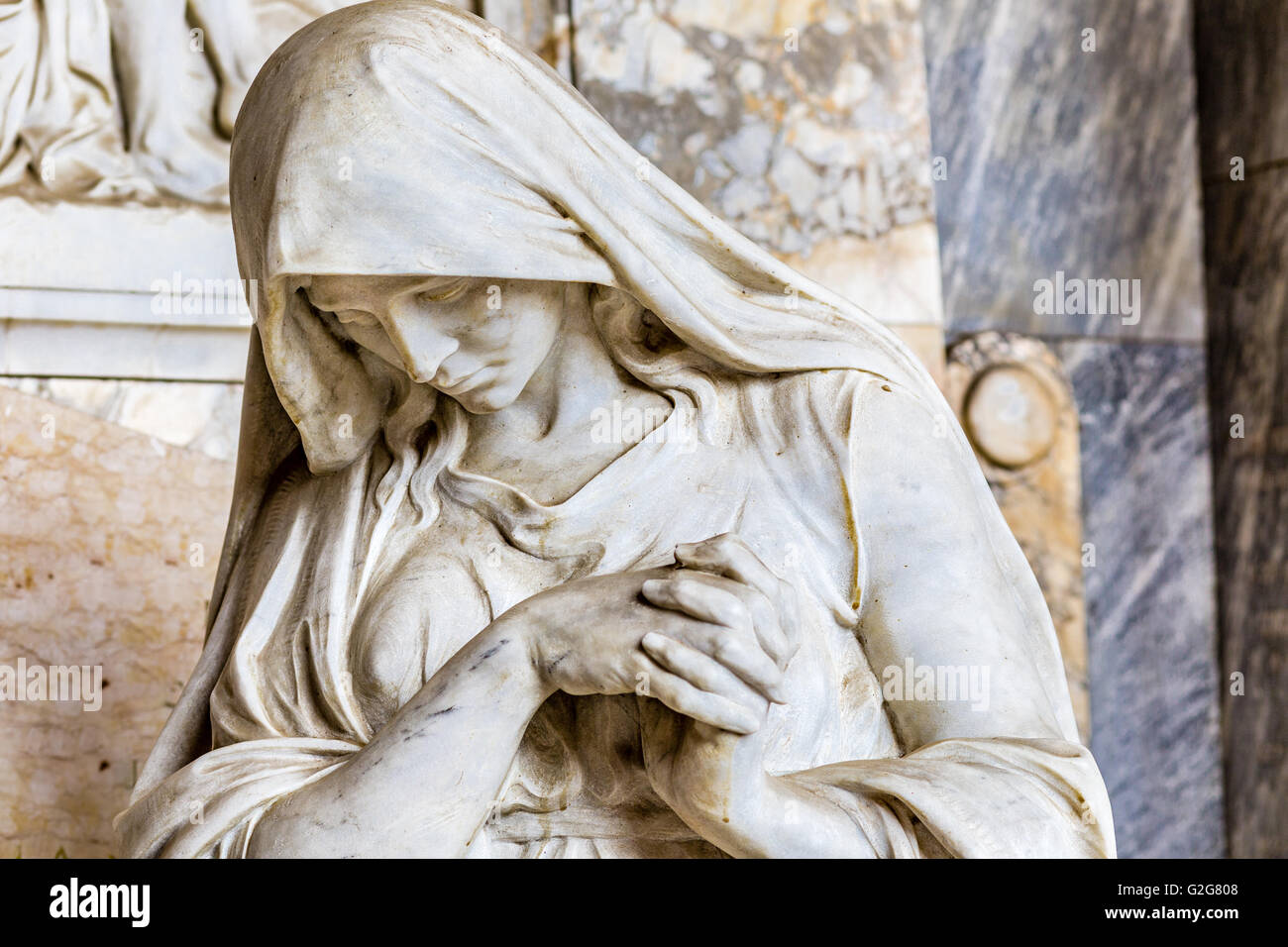 Details of statue of grieving woman with her hands clasped in prayer Stock Photo