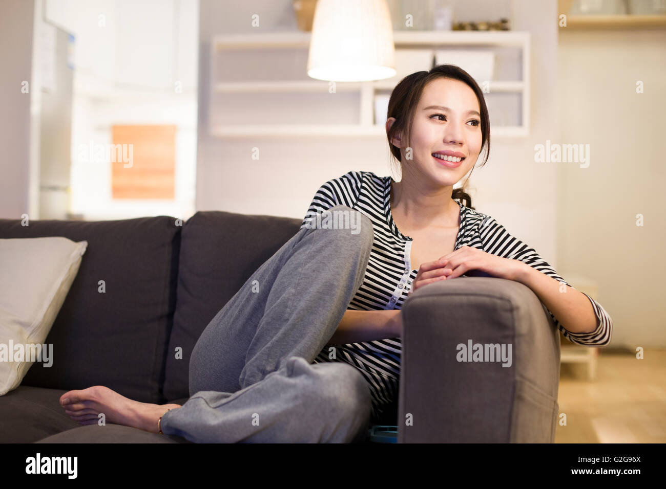 Young woman relaxing on living room sofa Stock Photo - Alamy