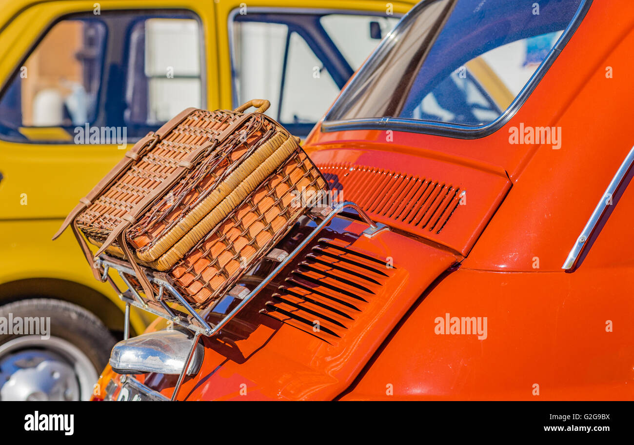 wicker suitcase on luggage rack of ancient Italian subcompact red car