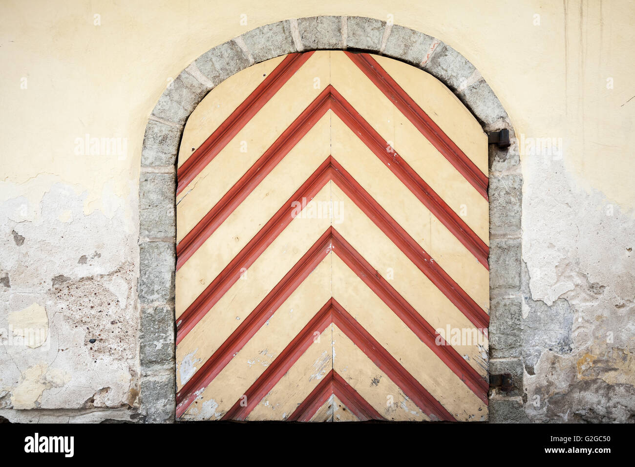 Ancient wooden door with red striped pattern in yellow stone wall ...