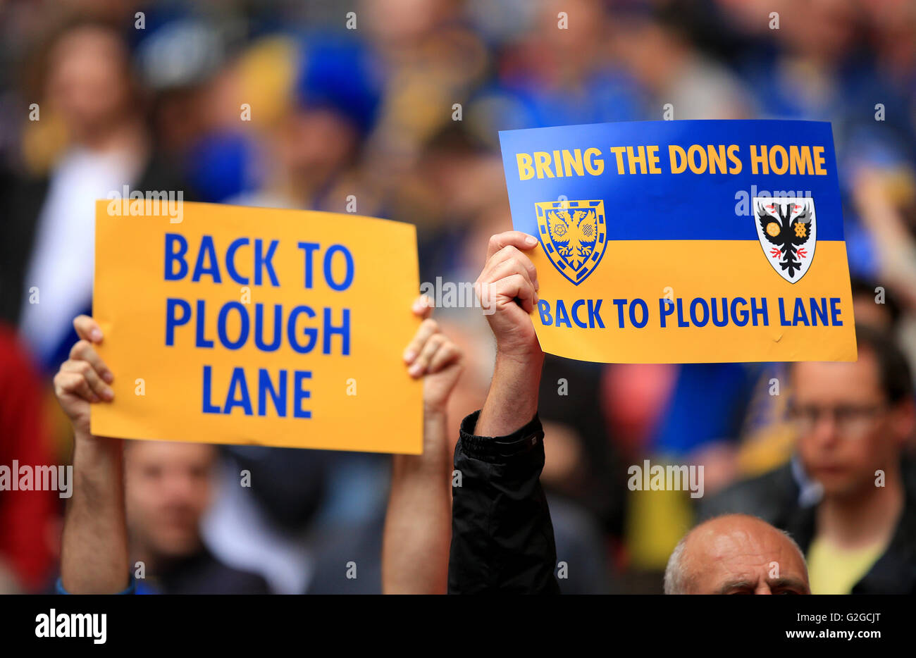 AFC Wimbledon fans hold signs asking for the club to return to it's former home before the Sky Bet League Two Play-Off Final match at Wembley Stadium, London. Stock Photo