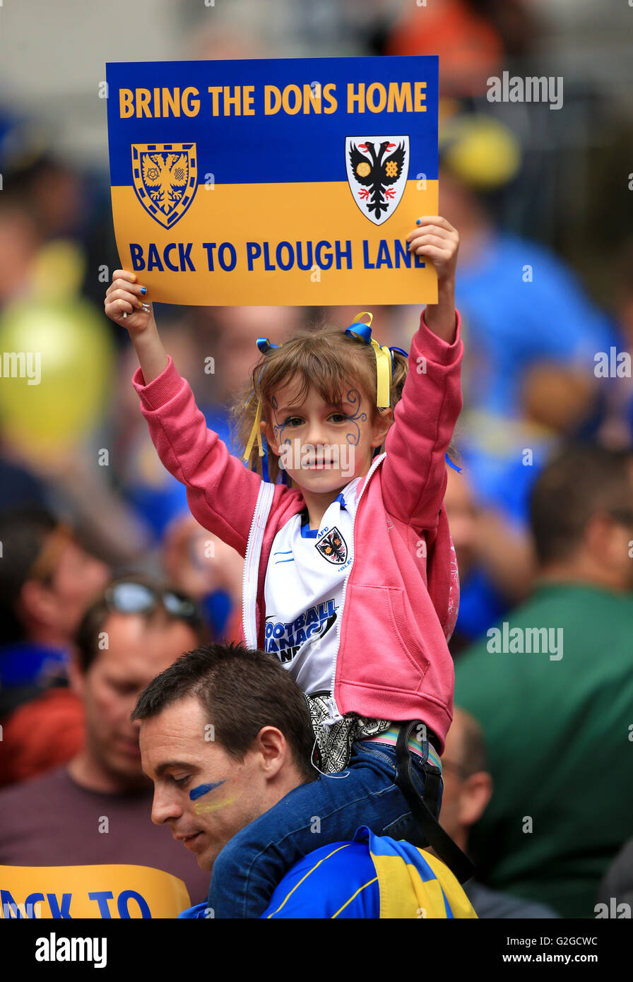 An AFC Wimbledon fan holds a sign asking for the club to return to its former home before the Sky Bet League Two Play-Off Final match at Wembley Stadium, London. Stock Photo