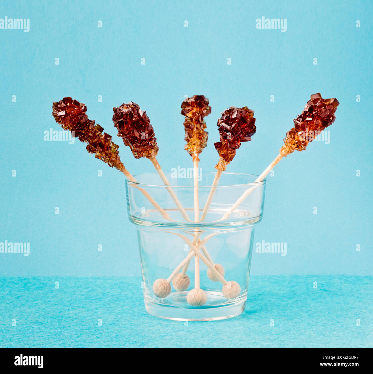 Five brown sugar stirrers in a glass on a light blue background. Stock Photo
