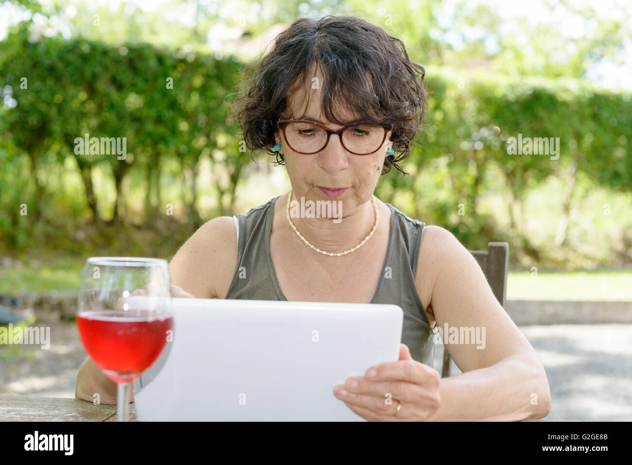 a charming  woman with a tablet in her garden Stock Photo