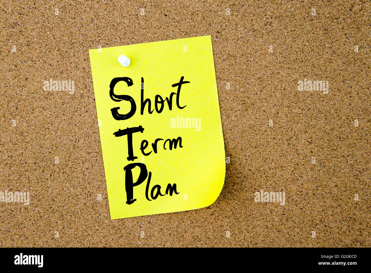 Business Acronym STP Short Term Plan written on yellow paper note pinned on cork board with white thumbtack, copy space available Stock Photo