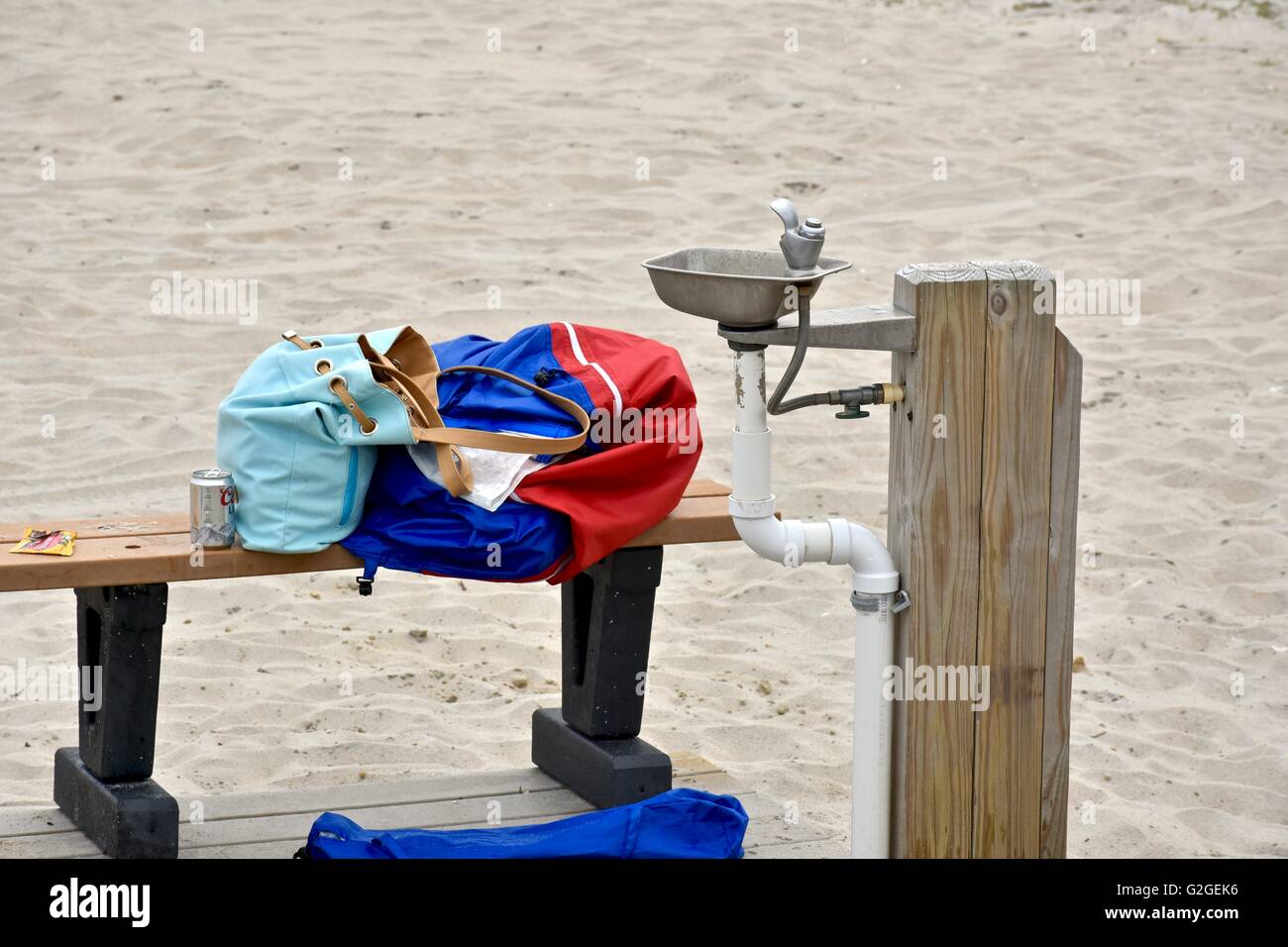 Articles of clothing and personal belongings left on a bench next to a water fountain at the beach at Assateague island Stock Photo