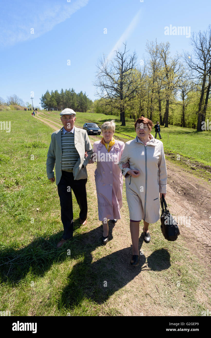 Three elderly pensioners walking on a track on a sunny day in bright sunlight during the summer of 2016 Stock Photo