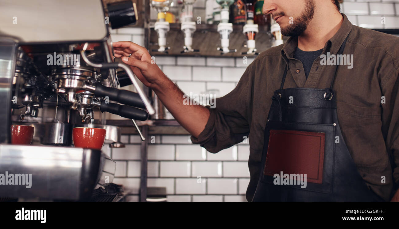 Cropped shot of male barista using a coffee maker to make a nice cup of coffee. Cafe worker preparing a coffee. Stock Photo