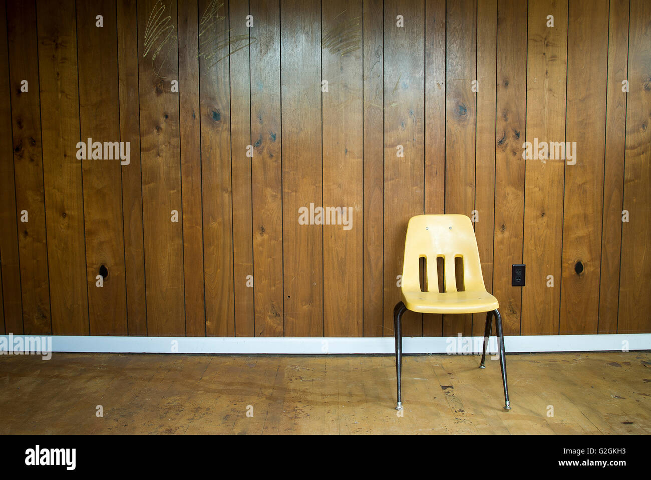 Yellow Chair Against Wall with Wood Paneling Stock Photo