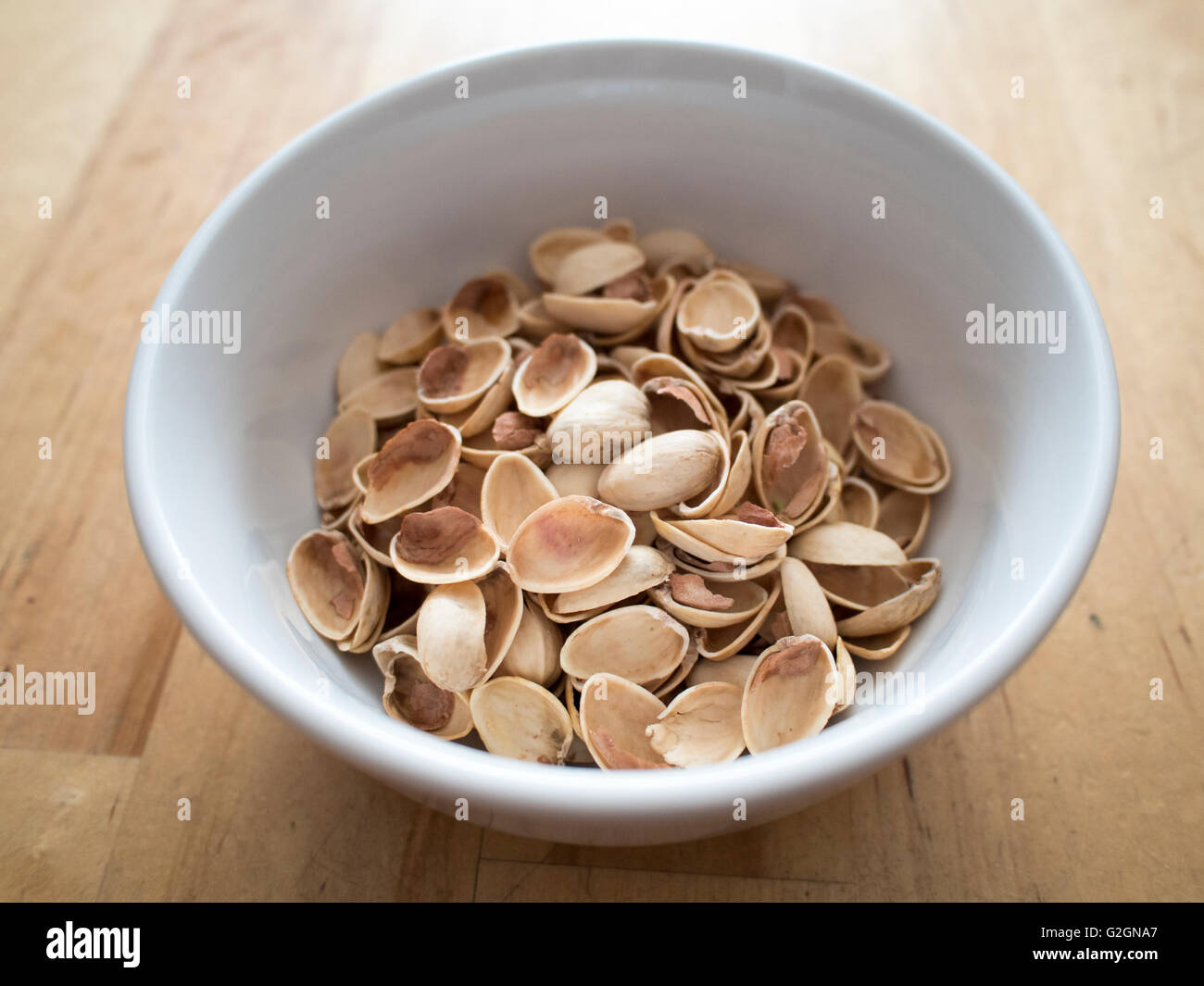 A bowl of pistachio shells in a white bowl. Stock Photo
