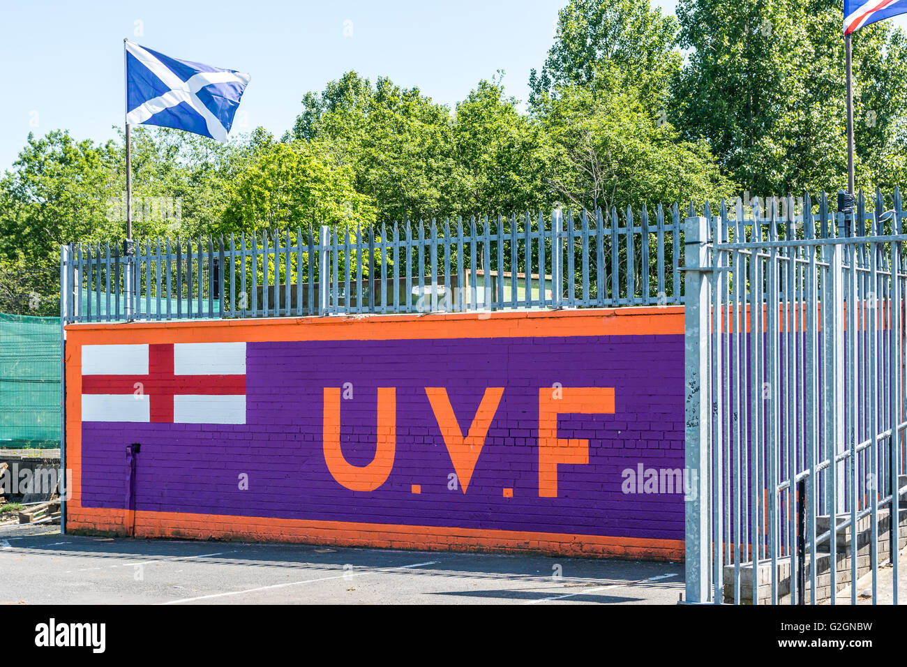 Large UVF mural in loyalist Sydenham area of East Belfast with Scotland's national flag flying overhead. Stock Photo