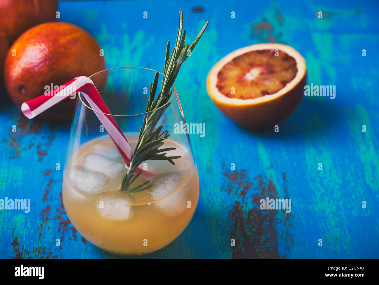 Fresh squeezed juice and blood oranges on blue background, tequila