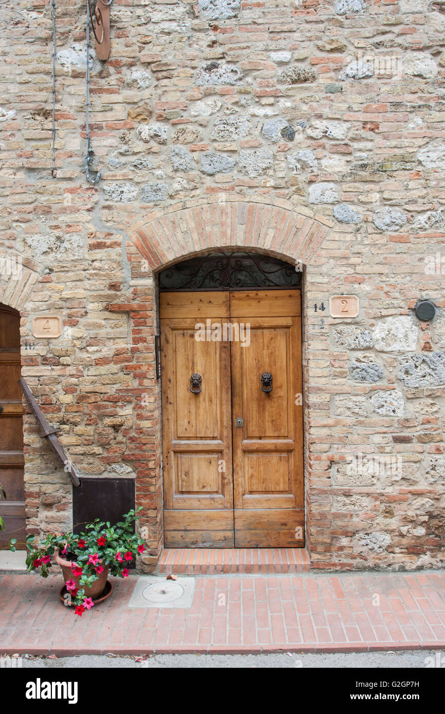 Image of classic wooden door with upper arch in a brickwall in small village, Italy. Stock Photo