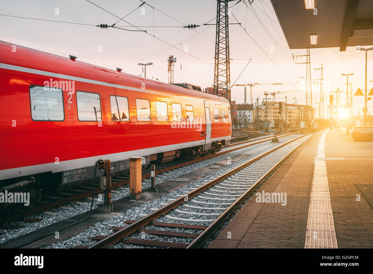 Beautiful railway station with modern red commuter train at colorful sunset in Nuremberg, Germany. Railroad with vintage toning Stock Photo