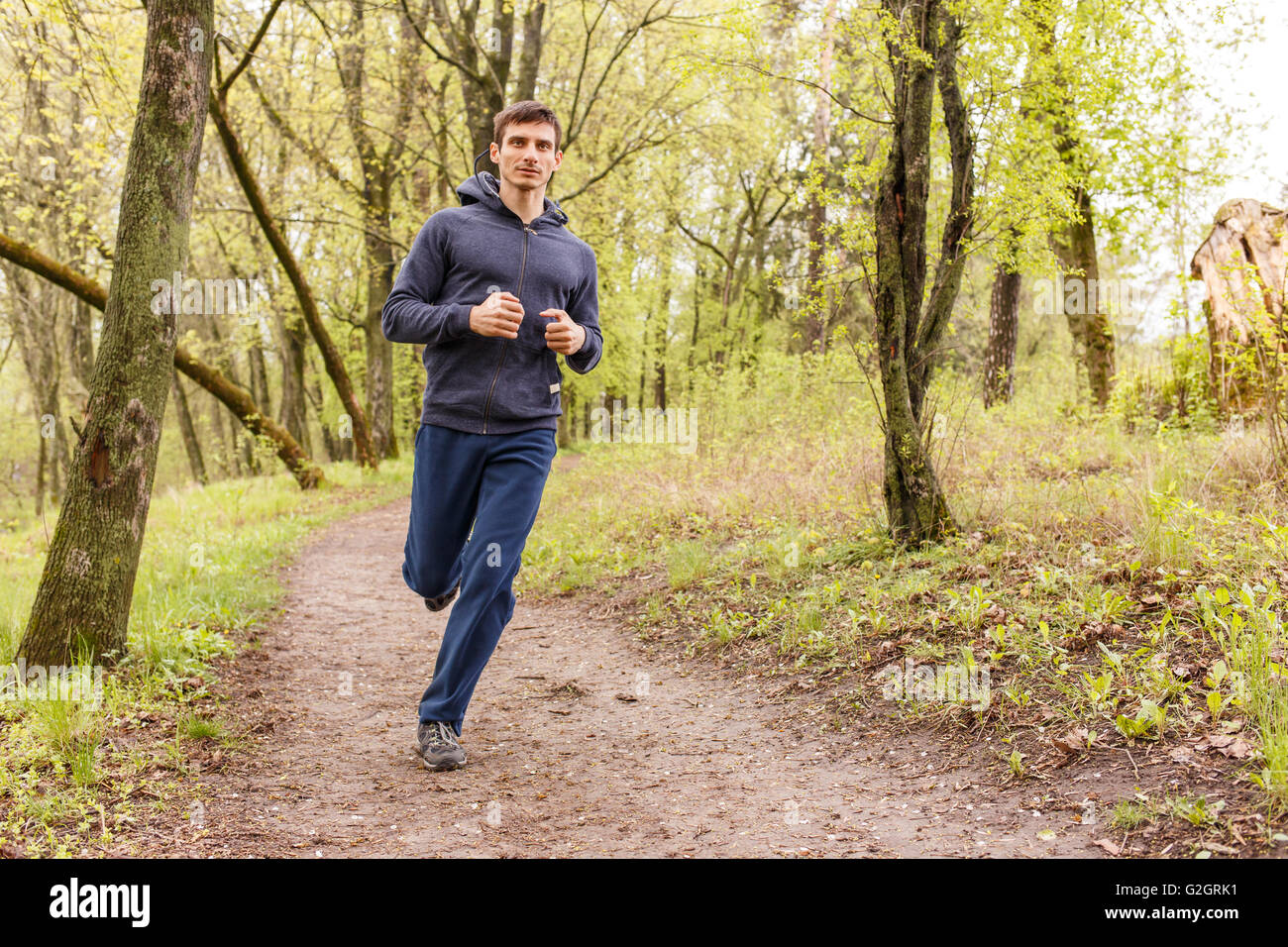 Young trail runner man jogging in the morning park. Sportsman running in the forest Stock Photo