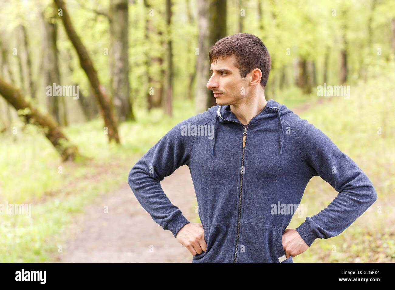 Young sportsman standing on the trail after jogging. Athletic man standing on running track Stock Photo