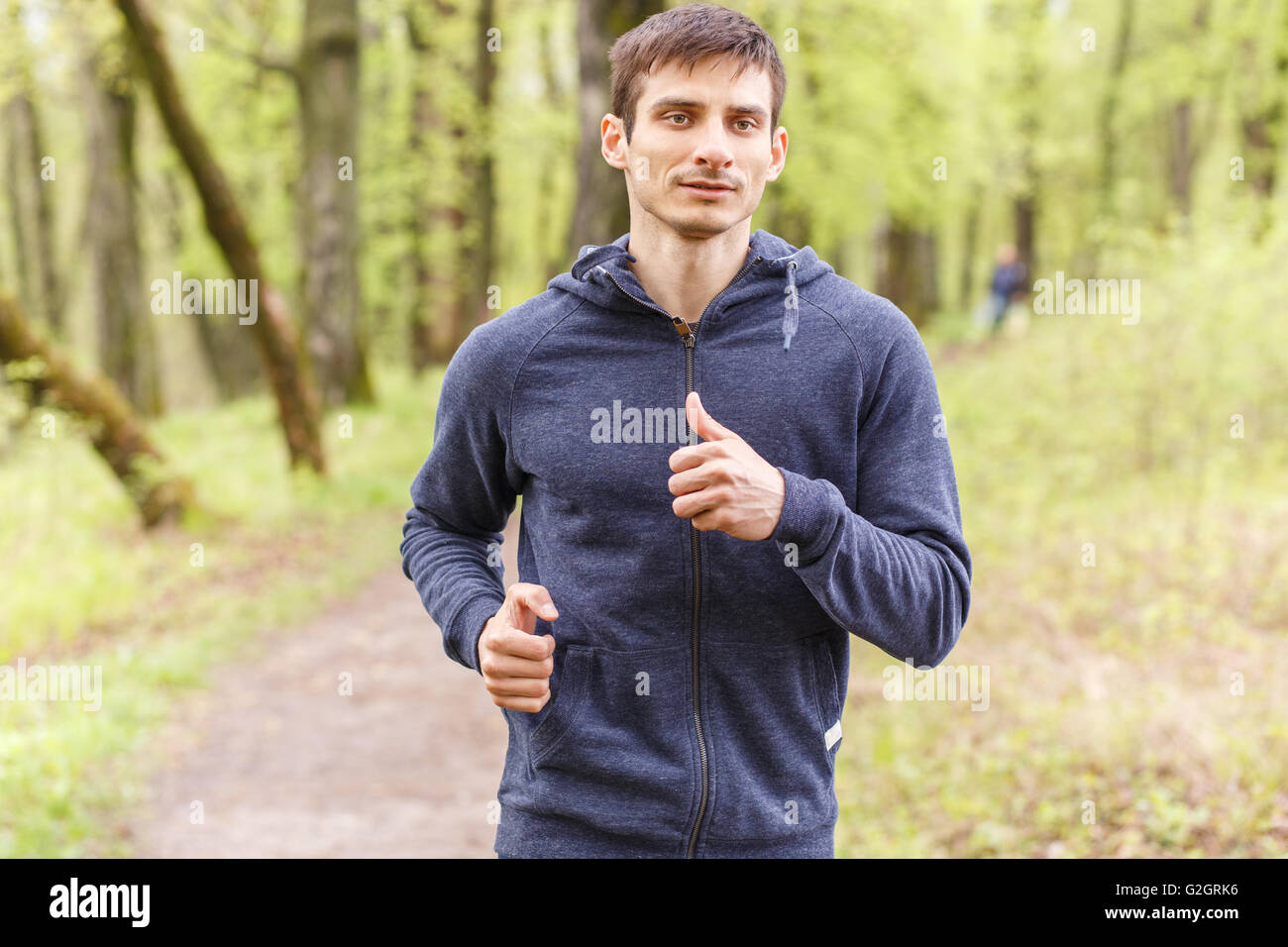 Young trail runner man jogging in the morning park. Sportsman running in the forest Stock Photo