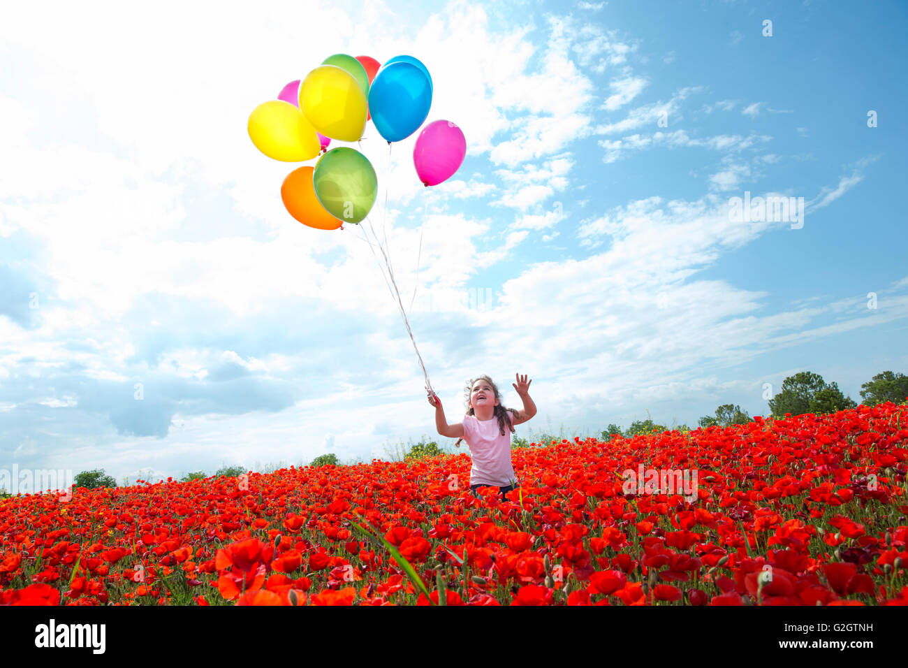 Little girl with balloons in bright red field in sunlight Stock Photo ...
