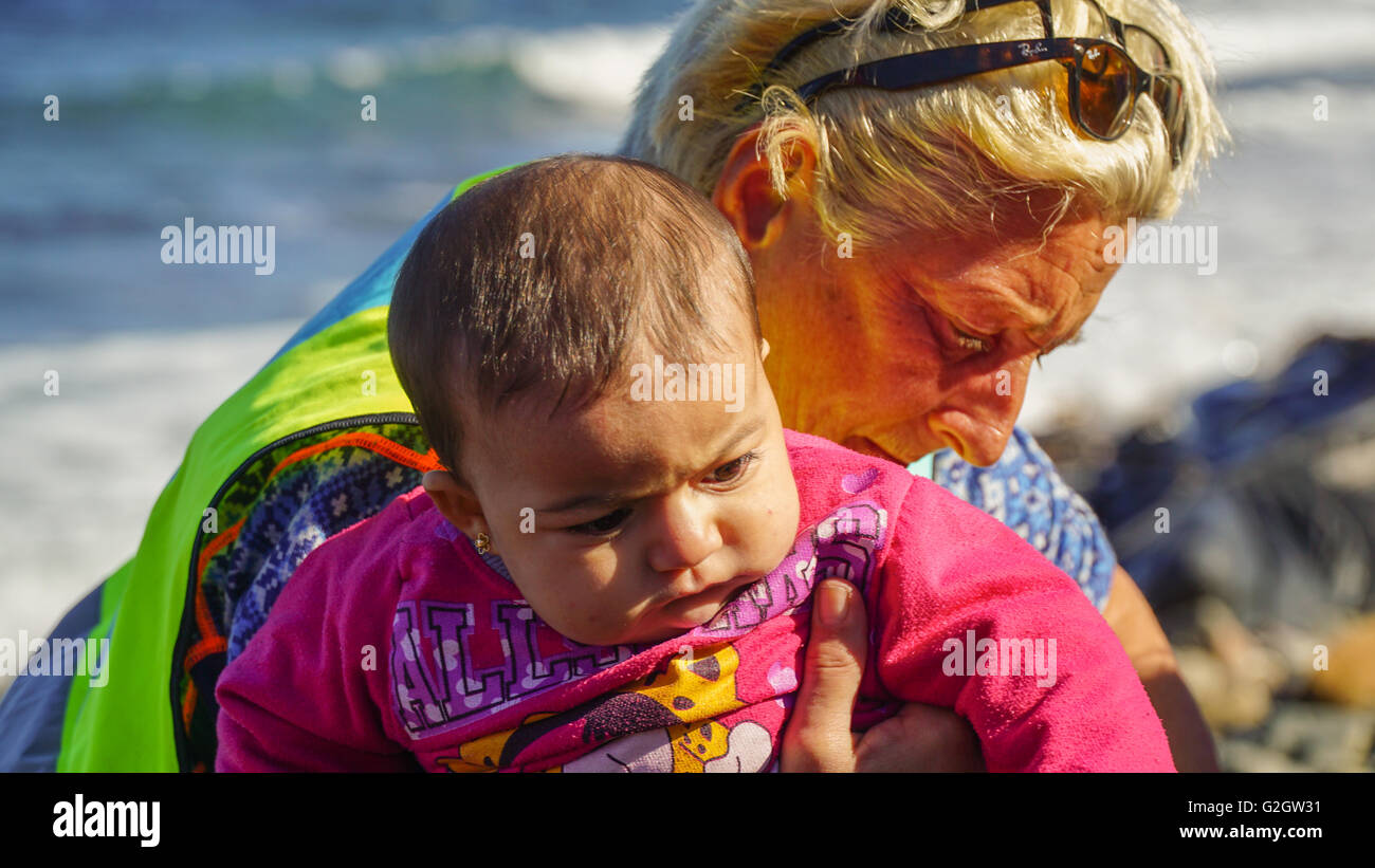 LESVOS, GREECE - October 10, 2015: A female volunteer with a small child-refugee Stock Photo