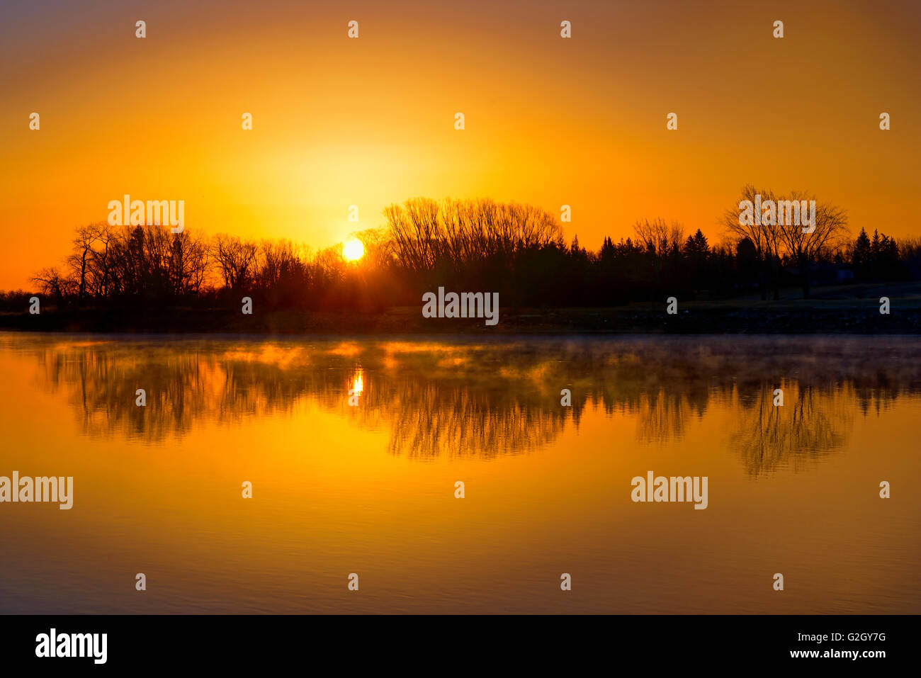 Reflection of trees in Red River at sunrise Lockport Manitoba Canada Stock Photo