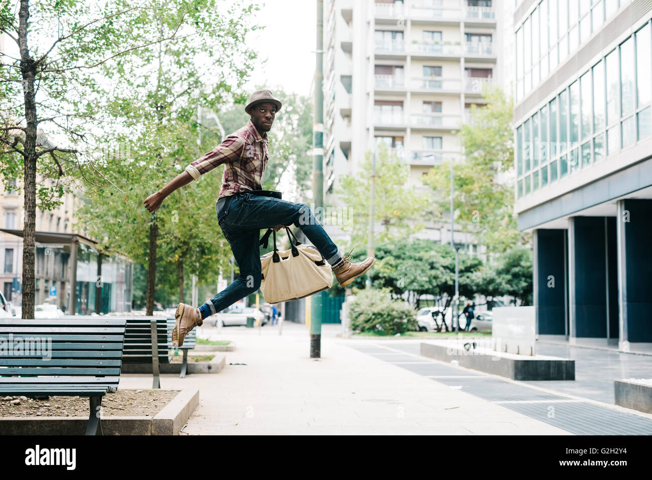 Young handsome afro black man jumping in the street of the city