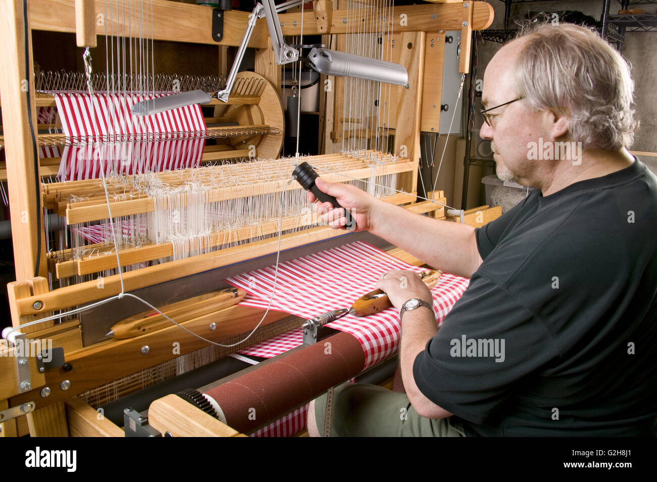 Man weaving checkered dish towels using fly shuttle on his AVL 16 shaft