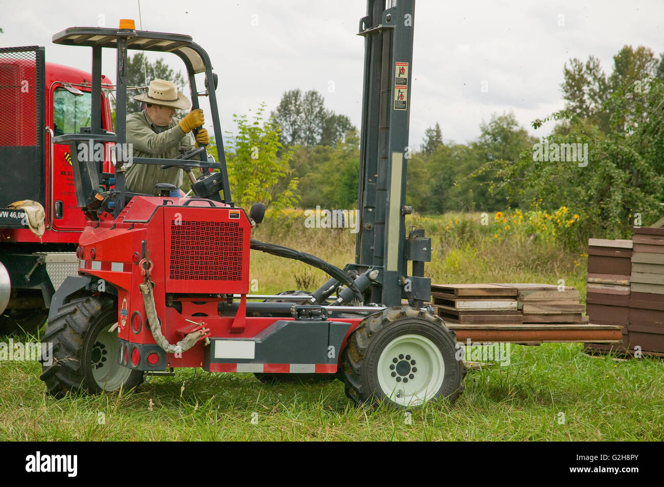 Man using his Moffett Mounty forklift to move pallet with hive covers near Redmond, Washington, USA Stock Photo