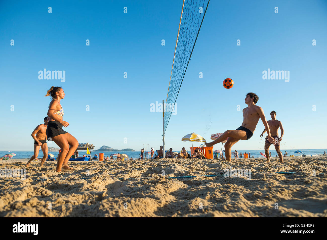 RIO DE JANEIRO - MARCH 17, 2016: Young carioca Brazilian men and women play a game of futevolei (footvolley) on Ipanema Beach. Stock Photo