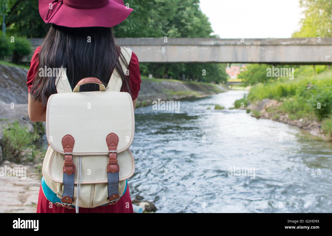 Girl with a backpack standing in front of a river Stock Photo