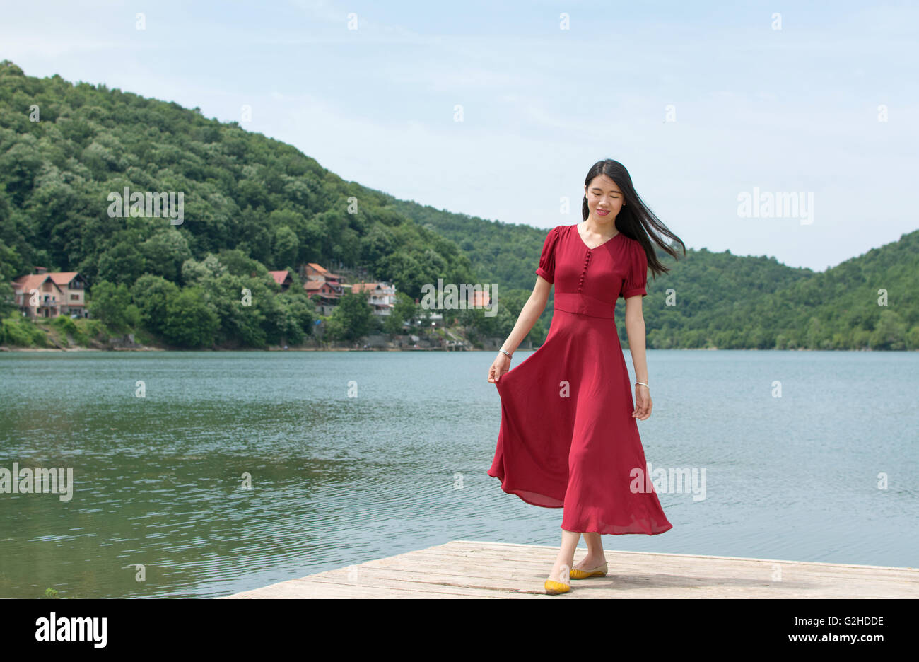 Fashionable woman standing in front of a lake alone Stock Photo