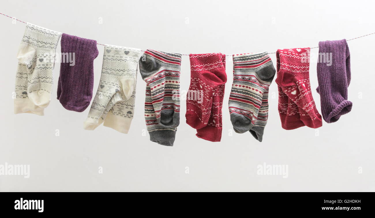 Various socks hanging from a wire indoors Stock Photo