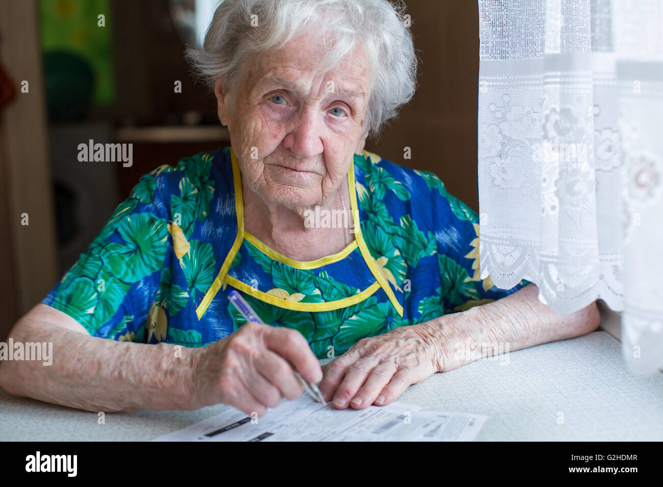 Elderly woman fills in receipts for utilities. Stock Photo