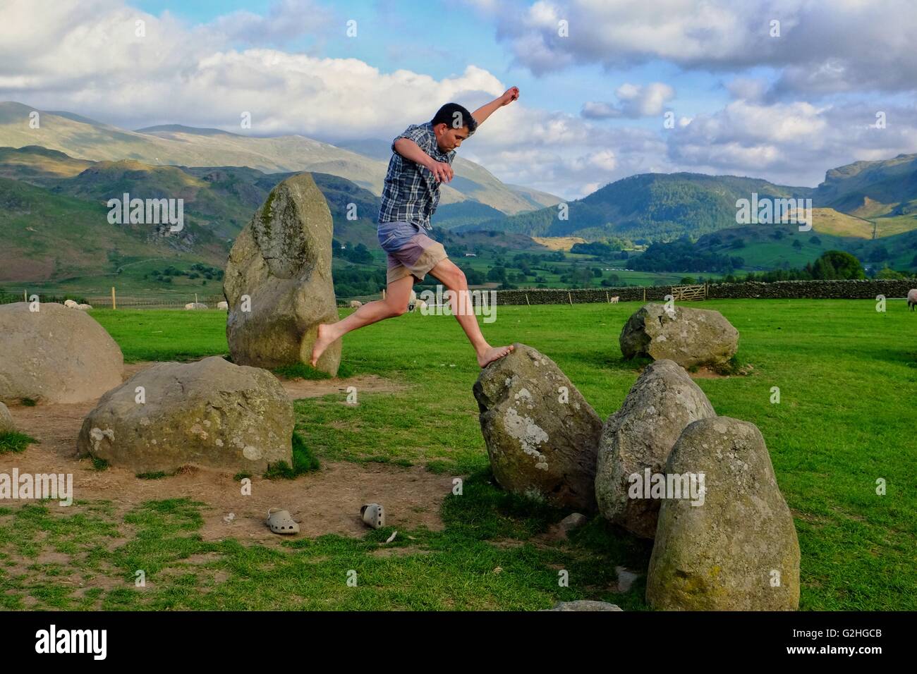 Castlerigg Stone Circle, Lake District, Cumbria, UK: 30 May 2016. A young man jumps across the stones in the late afternoon sun at Castlerigg Stone Circle after a day when crowds enjoyed a hot and suny Bank Holliday in the Lake District. Credit:  Tom Corban/Alamy Live News Stock Photo