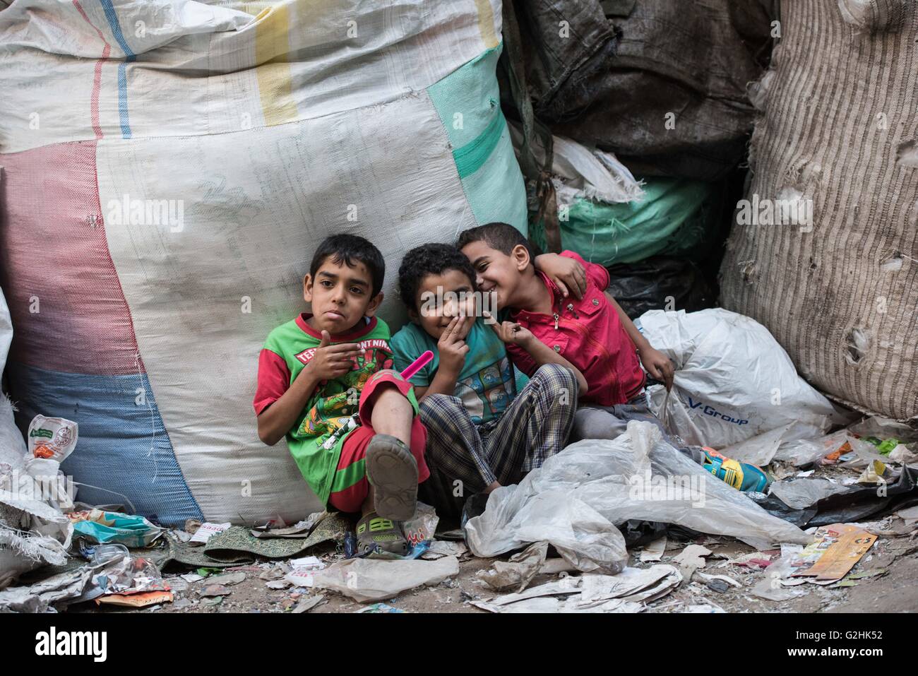 Cairo, Egypt. 27th May, 2016. Three boys sit among garbage at the Al-Mokattam City, also known as the 'Garbage City', in Cairo, capital of Egypt, on May 27, 2016. Living on the outskirts of Cairo, the Zabalen, which literally means 'garbage people', is a community that has been collecting and recycling Cairo's waste for a long time. They collected and sorted the waste for a living at Al-Mokattam City. The children here live and play among the garbage and lots of them have dropped out of school to help their family's garbage business. © Meng Tao/Xinhua/Alamy Live News Stock Photo