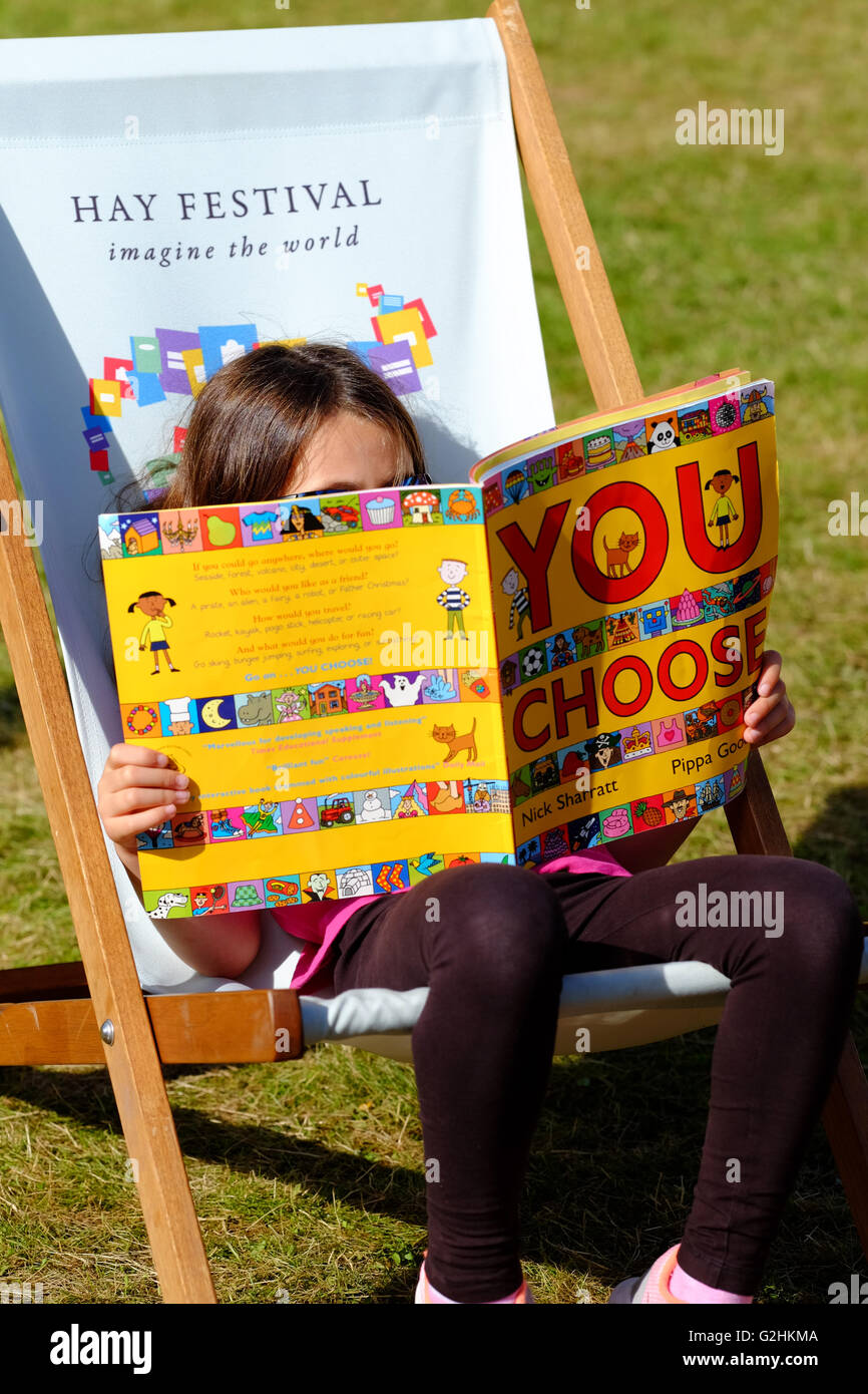 Hay Festival, Wales, UK - May 2016 -  A young girl sits and reads her new book on the Festival lawns. Stock Photo