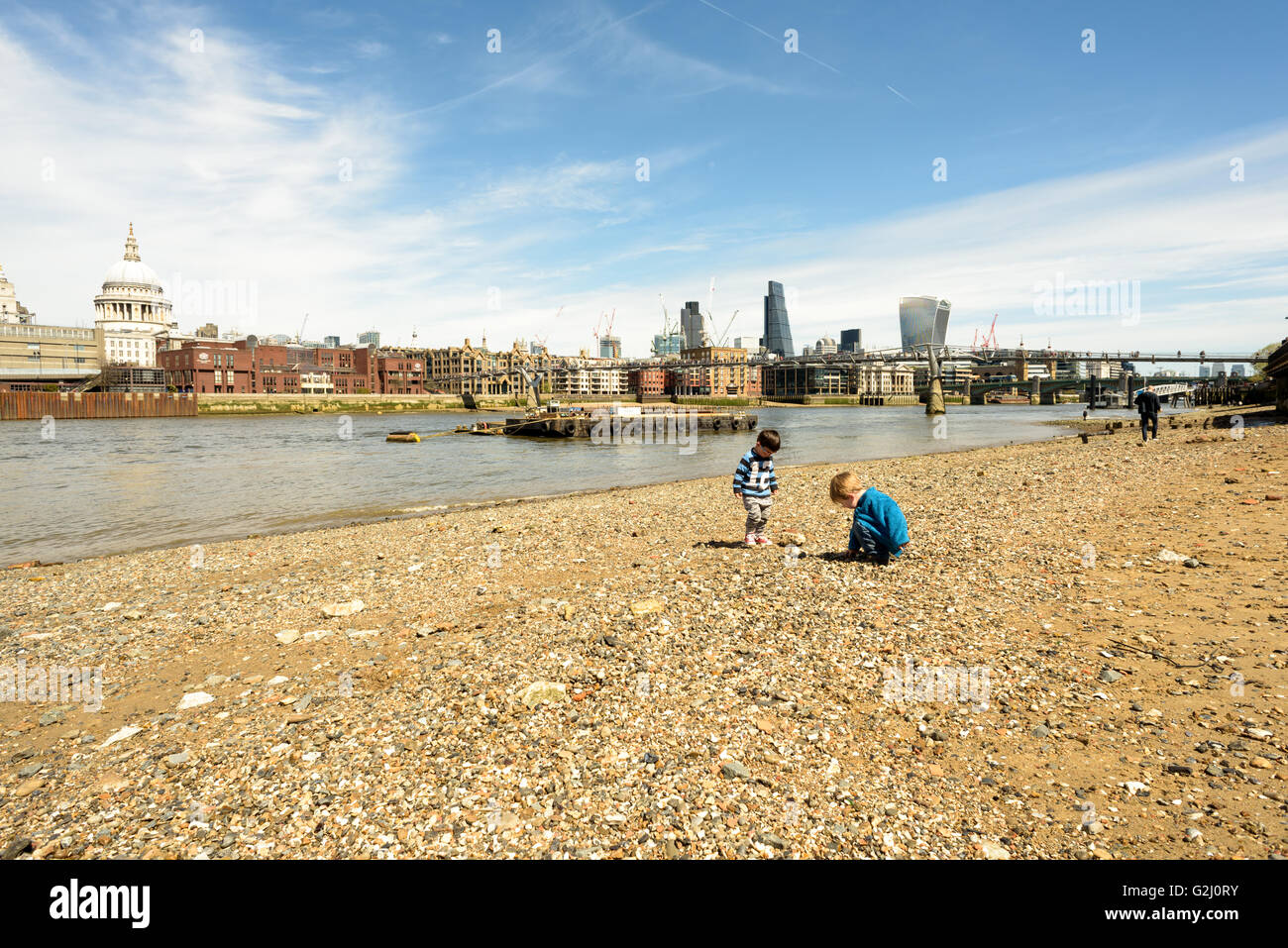 Two children play on the sandy shores of the River Thames in London at Low Tide in May sunshine 2016 Stock Photo
