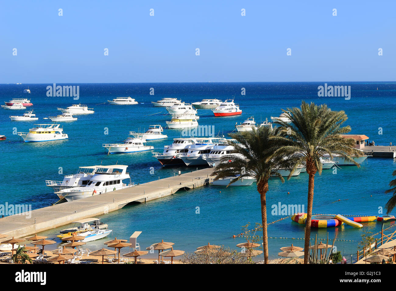 Yachts, and beach area with sun shades and lounging chairs at a resort on the Red Sea in Hurghada, Egypt Stock Photo