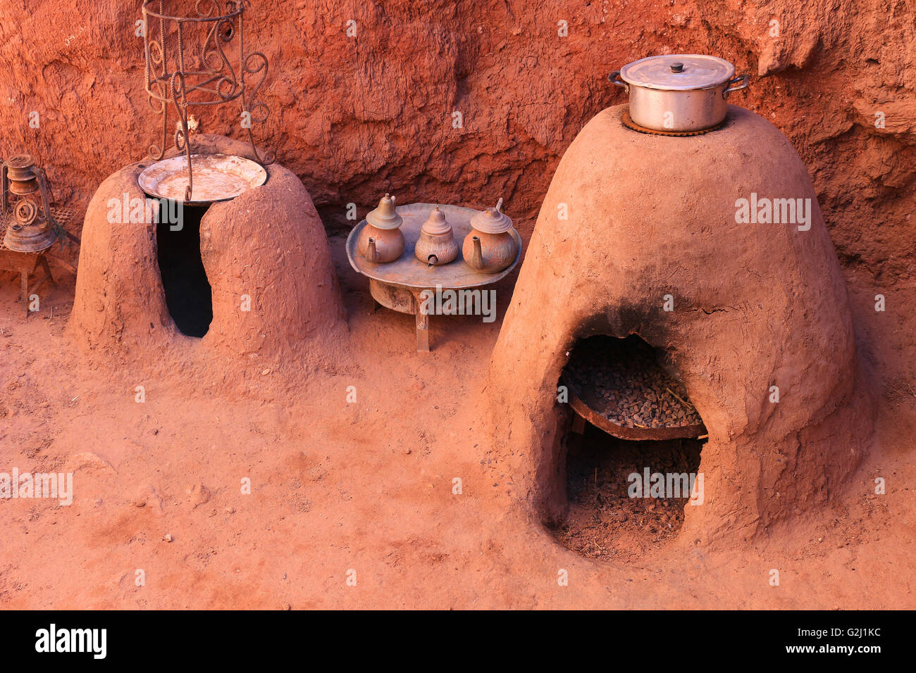 Traditional Moroccan earth ovens made out of sandstone with a pot cooking food  and tea kettles Stock Photo