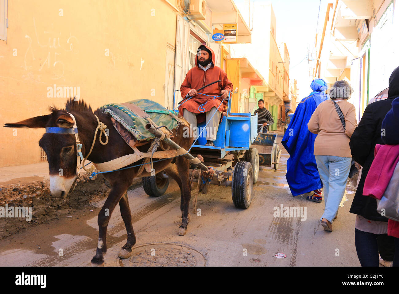 RISSANI, MOROCCO: Narrow street in Rissani with donkey cart and colorful clothes people in Morocco Stock Photo