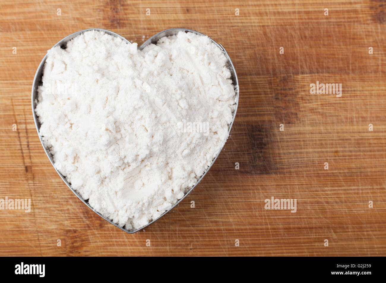 Flour shape heart in a mold on brown wood cutting board Stock Photo