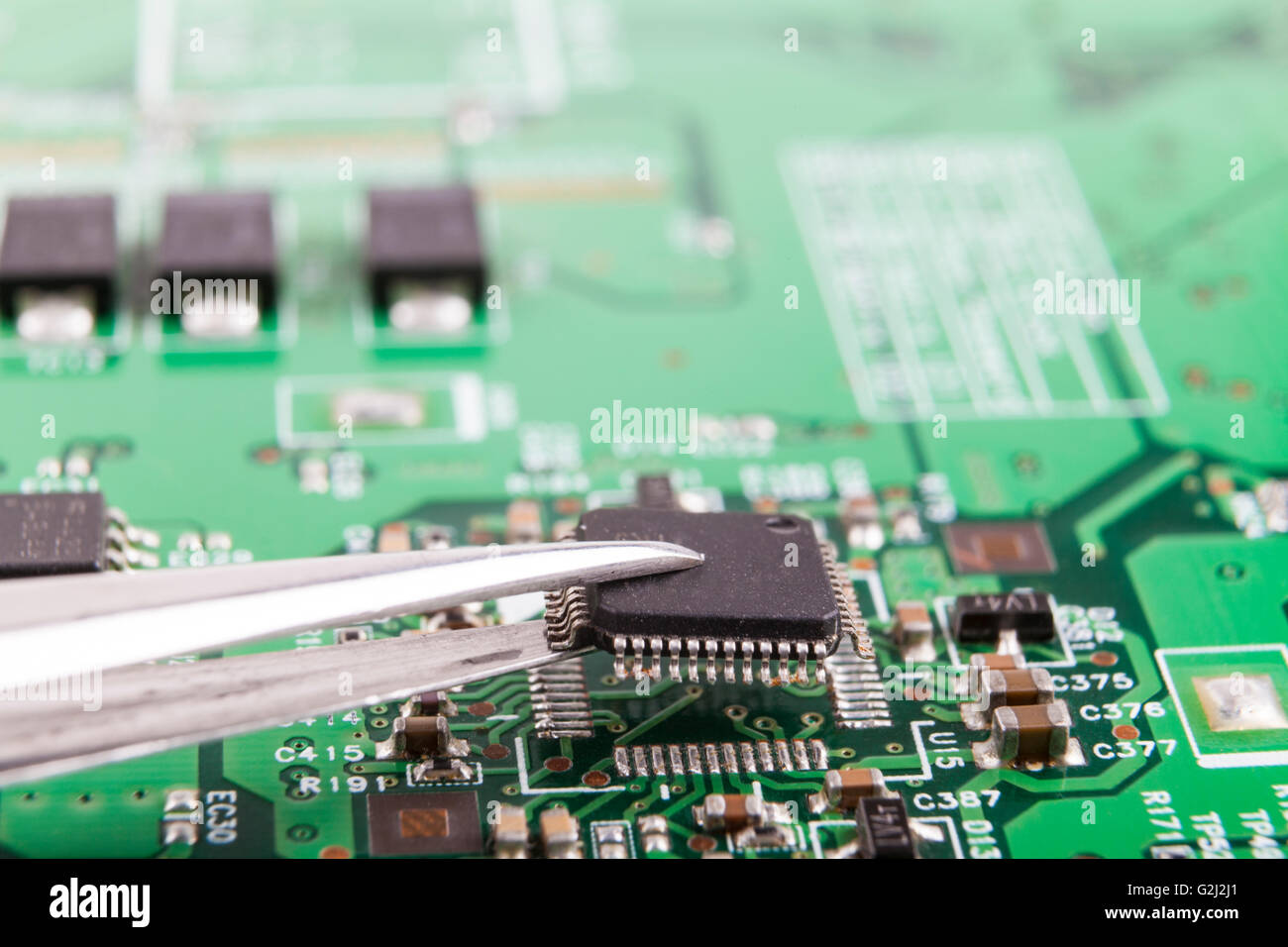 Mounting microchip on electronic circuit board with tweezers Stock